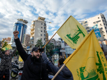 Residents celebrate carrying Hezbollah's flags in Dahiyeh, Beirut, Lebanon, following a ce