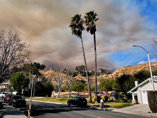 A large plume of smoke rises from Castaic Lake seen behind a neighborhood in Santa Clarita