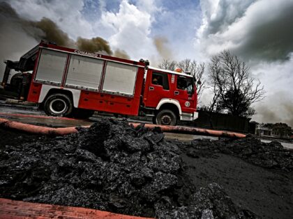 Firefighters work in the area where the massive fire at a fuel depot sparked by a lightnin