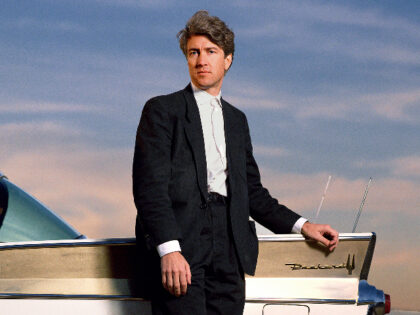 Director David Lynch stands outdoors in front of Packard vehicle in Los Angeles in 1986. (