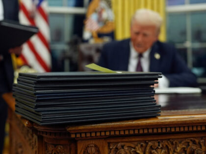 President Donald Trump signs executive orders in the Oval Office of the White House, Monda