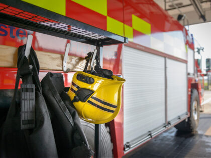 Firemans helmet hanging by fire engine in fire station - stock photo