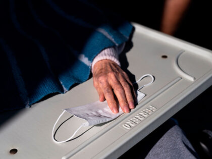 An elderly resident puts her hand on a face mask within the visit of relatives at the Tapp