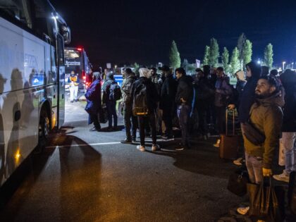 Asylum seekers board a bus to the emergency shelter at the application center in Stadskana