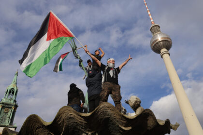 BERLIN, GERMANY - NOVEMBER 04: A man waves a Palestinian flag from atop Neptune Fountain d