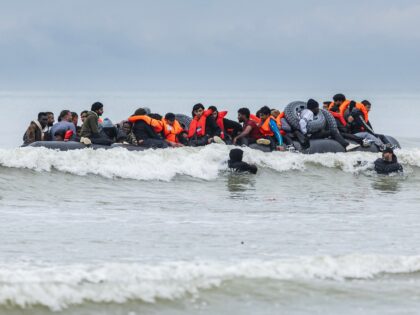 Migrants try to board a smuggler's inflatable dinghy in an attempt to cross the English Ch