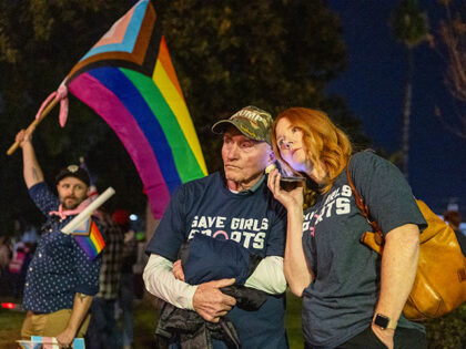 Transgender athlete supporter Kyle Harp, left, of Riverside holds the progress pride flag