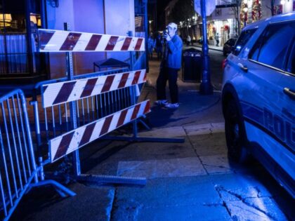 A man takes photos of a blocked off street near Bourbon Street, after at least 15 people w