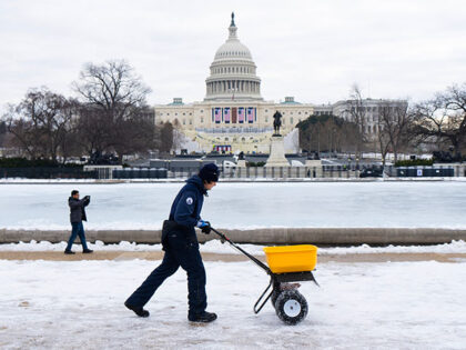 An Architect of the Capitol worker spreads de-icer around the Capitol Reflecting Pool on M