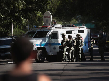 Residents watch as Chicago Police SWAT team members surround a house in the Humboldt Park