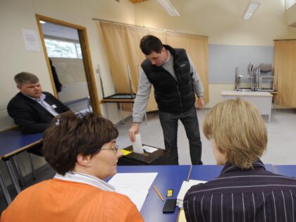 Voting officers chat as an Icelander casts his ballot at a polling station in Reykjavik on