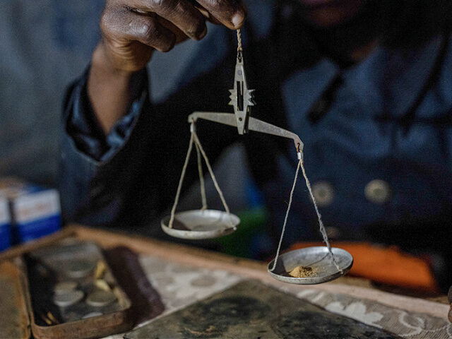 Gold trader Siri Munga Walubinja holds a gold scale in his buying house in Kamituga, in th