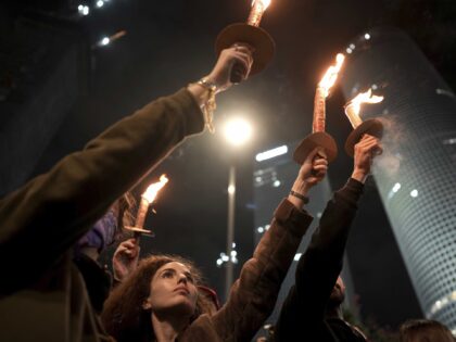 Demonstrators hold torches as they gather during a protest calling for the release of all