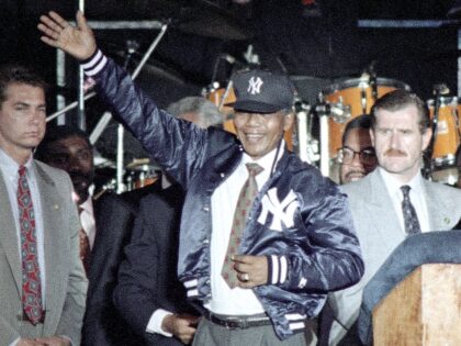 Nelson Mandela acknowledges the crowd after donning a New York Yankees warm-up jacket and