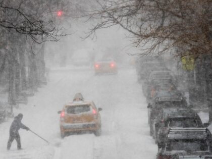 A man shovels snow as traffic makes it's way east on 81st street, Thursday, Jan. 4, 2