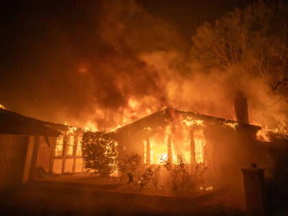 Flames from the Palisades Fire burn a home during a powerful windstorm on January 8, 2025