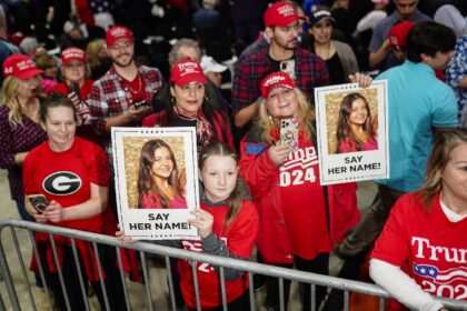 Supporters of President-elect Donald Trump brandish images of Laken Riley at a 2024 campai