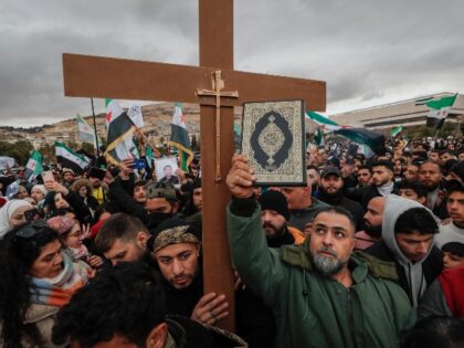 Syrians hold a copy of the Quran next to a Christian cross during a demonstration in suppo